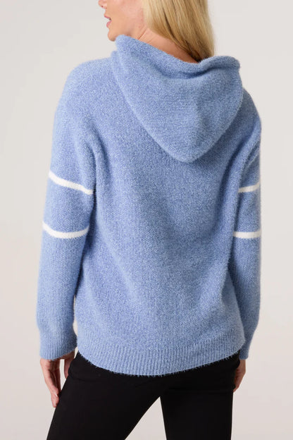 Person seen from behind wearing a cosy baby blue hoodie with white stripes down the sleeves, paired with black trousers.