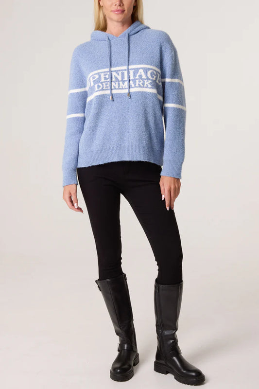 Person wearing a cosy baby blue hoodie with PENNNAGE DENMARK text, black leggings, and black knee-high boots, standing against a plain background.