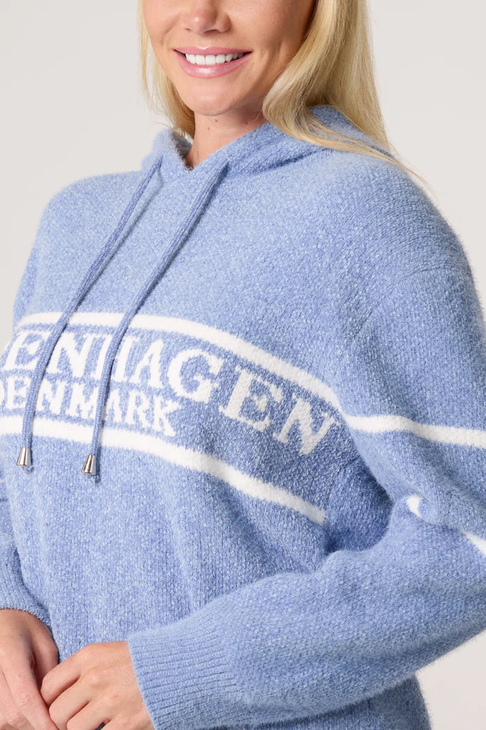 A person wearing a cosy baby blue hoodie with white stripes and the words COPENHAGEN DENMARK printed on the front.
