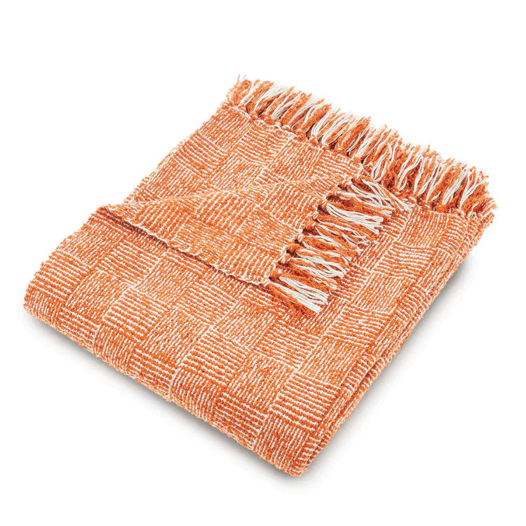 Folded woven cross-hatch rust throw featuring an orange and white chequered pattern and fringe detailing along the edges, shown against a white background.