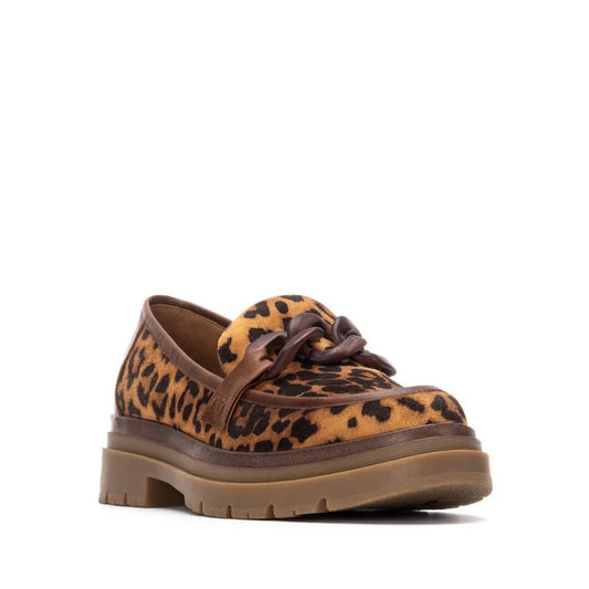 A women’s moccasin in leopard print with a chunky brown sole and a decorative chain on the upper, made from high-quality imitation leather for a striking, vegan-friendly statement.