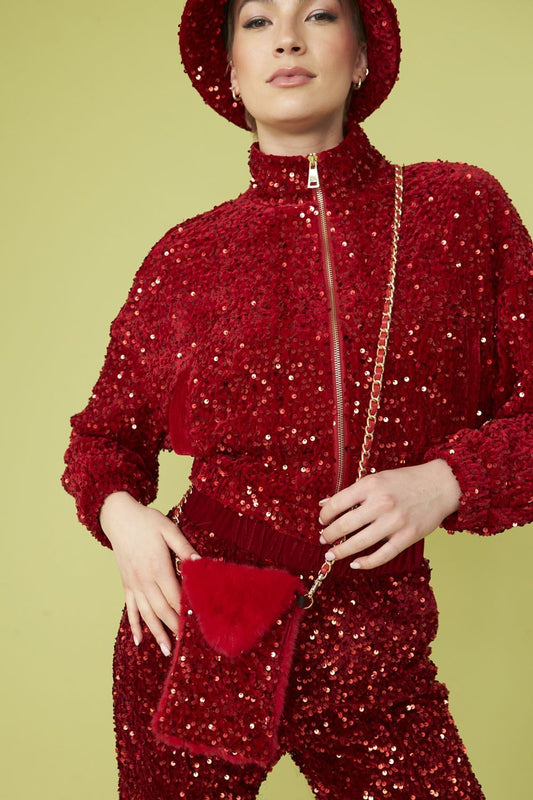 Person wearing a red sequinned outfit and matching bucket hat, holding a Sequin Phone Holder Bag with a gold chain strap, standing against a light green background.