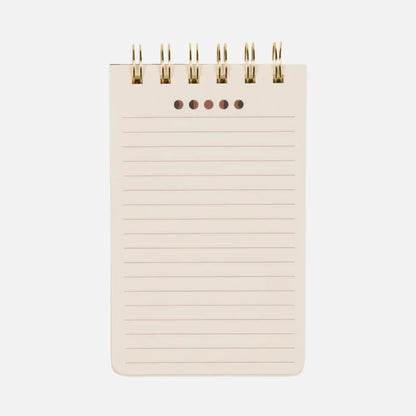 A small, spiral-bound flip notebook with lined pages and five holes at the top, photographed against a plain white background.
