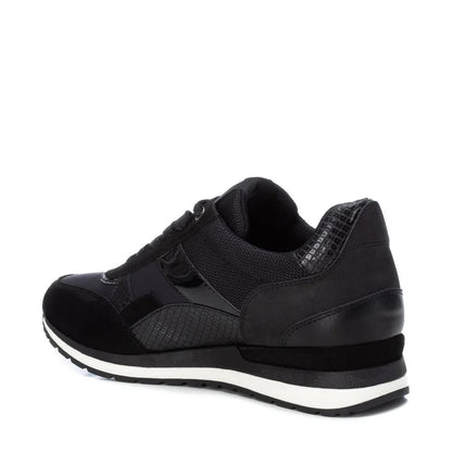 A black women’s trainer made from PETA-certified vegan materials, featuring a mixed-texture design, laces, a removable insole, and a sole with white stripes, viewed from a back-side angle.
