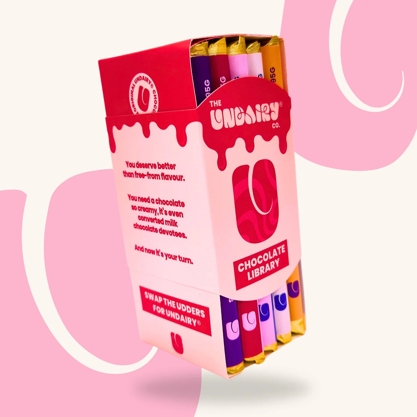 A box labelled The Udairy Co. Chocolate Library containing several colourful chocolate bars, including the Fruit & Nut bar and the Original Creamy bar, with stylised branding and text on the packaging.