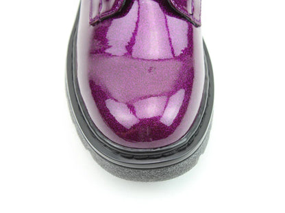 Close-up of the shiny purple toe of a vegan-friendly shoe with black rubber sole, photographed against a white background.