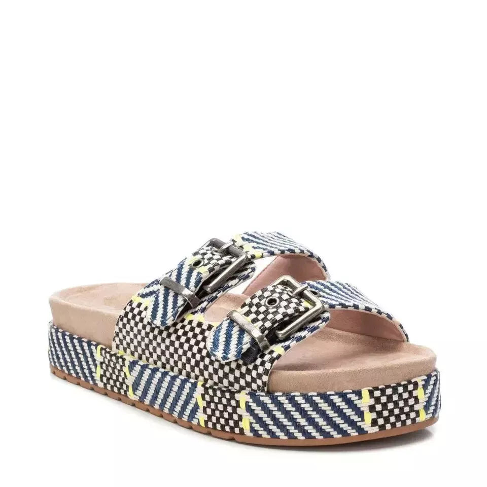 A pair of double buckle sandals with a platform sole, featuring woven, multicoloured geometric patterns, two adjustable buckle straps, and a cushioned footbed.