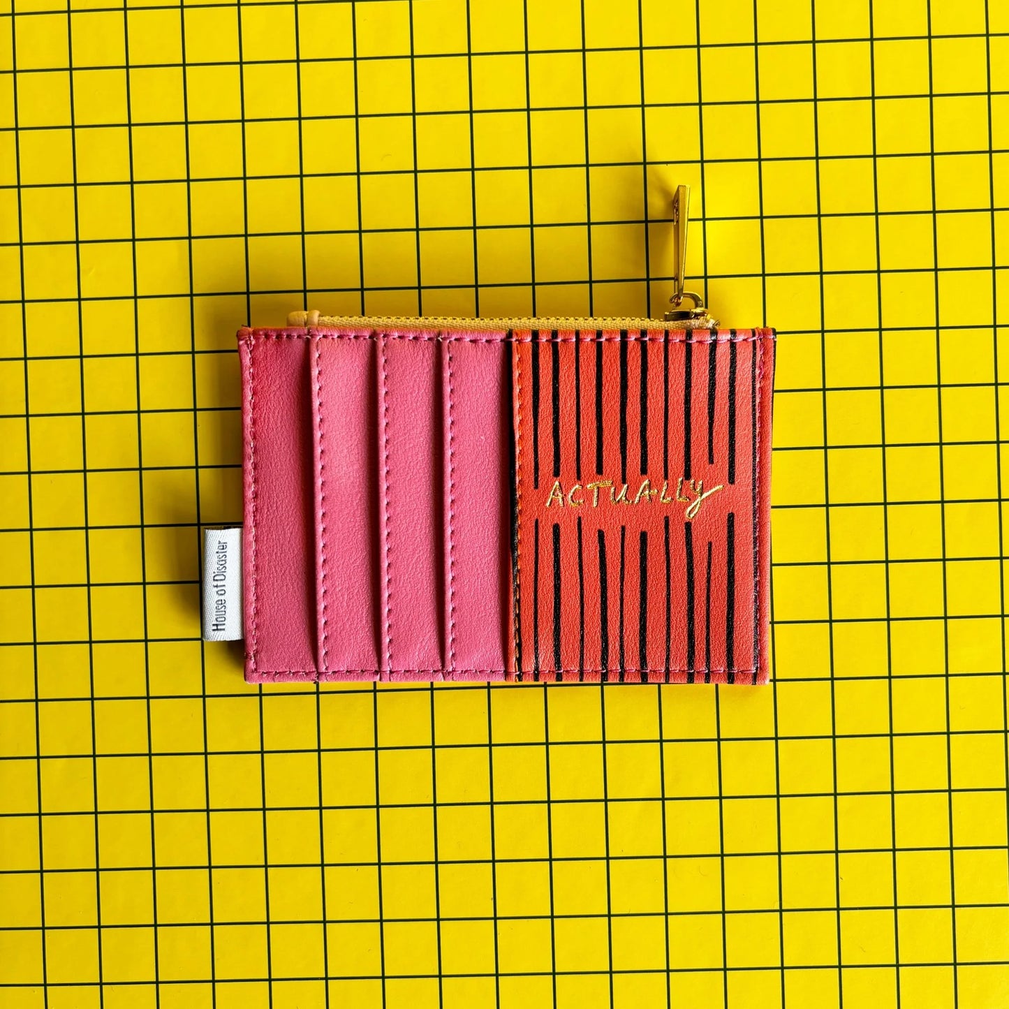 A pink and black striped cheeky zip purse labelled ACTUALLY sits on a yellow grid-patterned background, making an amusing gift for anyone who loves quirky style.
