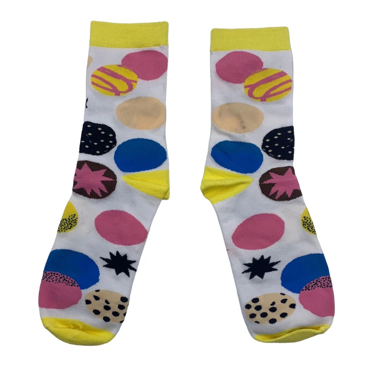 A pair of white bamboo socks with yellow cuffs, toes, and heels, adorned with colourful circles and starburst patterns in pink, blue, beige, black, and yellow.