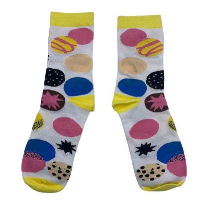 A pair of white bamboo socks with yellow cuffs, toes, and heels, adorned with colourful circles and starburst patterns in pink, blue, beige, black, and yellow.