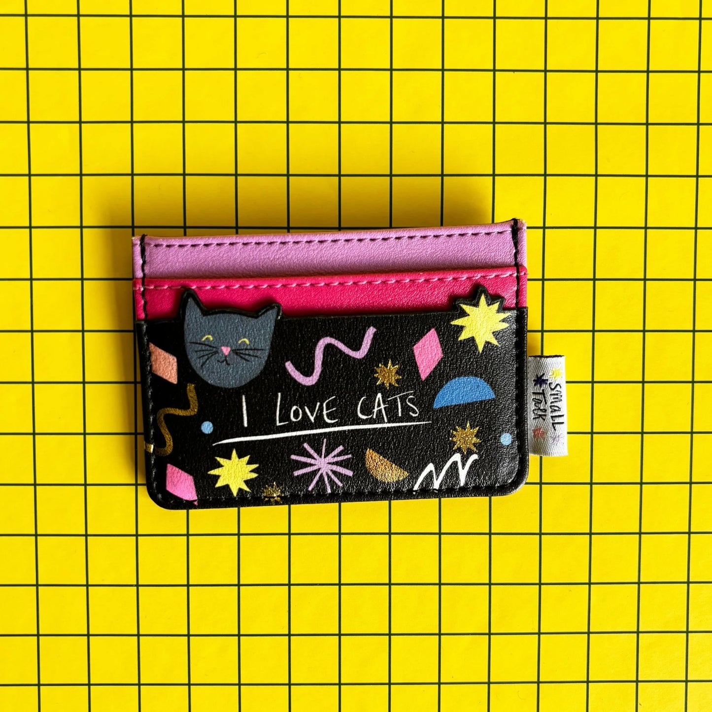 A compact PVC cat card holder in black and pink, featuring playful patterns, a cat illustration, and “I LOVE CATS” text, set against a yellow chequered background—ideal as a present for cat lovers.