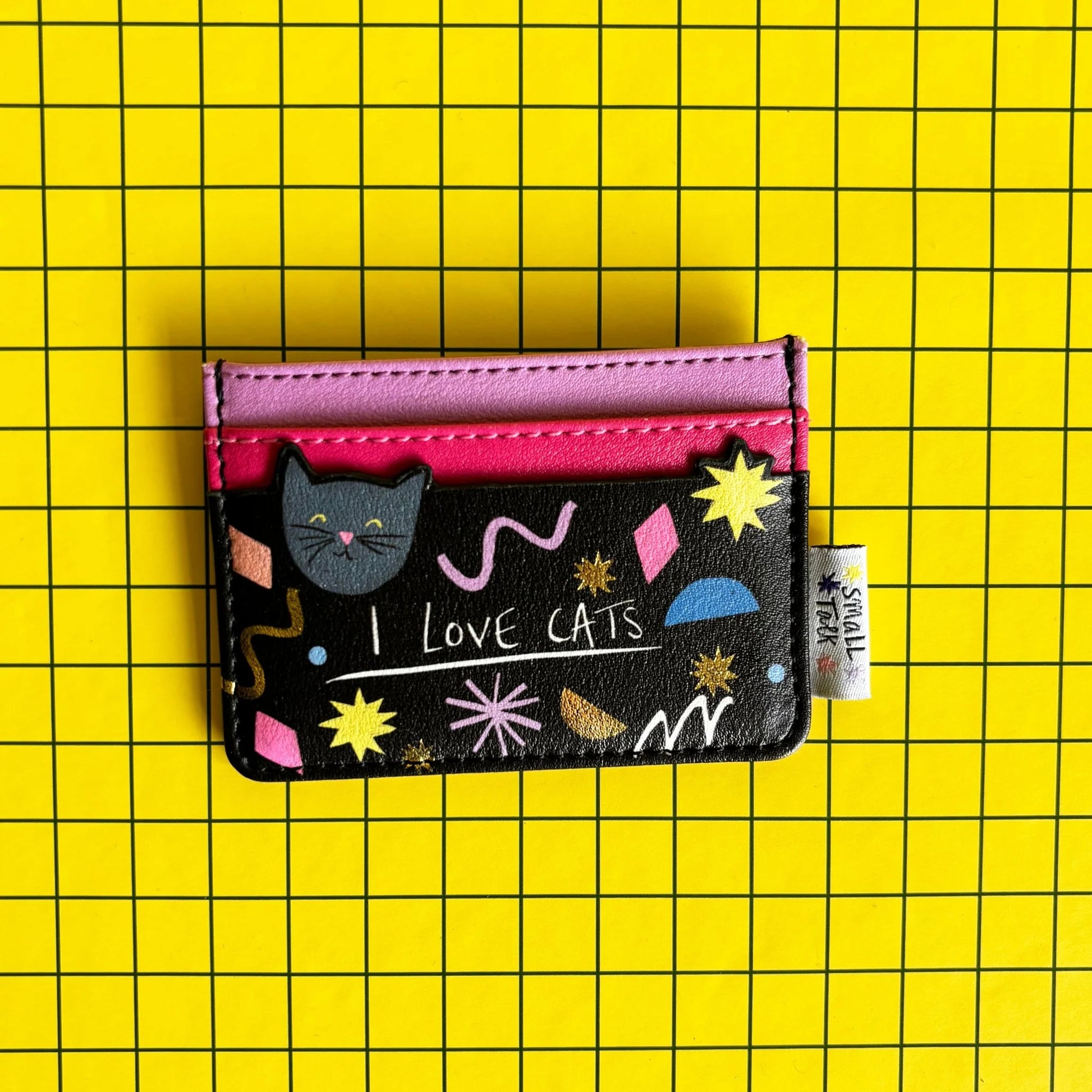 A compact PVC cat card holder in black and pink, featuring playful patterns, a cat illustration, and “I LOVE CATS” text, set against a yellow chequered background—ideal as a present for cat lovers.