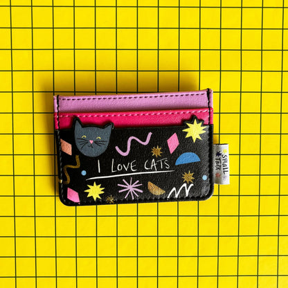 A compact PVC cat card holder in black and pink, featuring playful patterns, a cat illustration, and “I LOVE CATS” text, set against a yellow chequered background—ideal as a present for cat lovers.