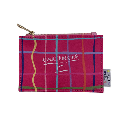 A small pink zippered pocket-sized purse featuring a multicoloured plaid pattern and the words OVER THINKING IT. printed on the front—a witty gift with a SMALL TOK tag attached to the side.