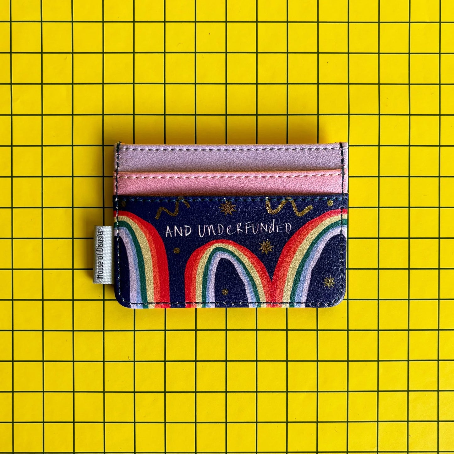 A multicoloured, pocket-sized cardholder with pink slots and AND UNDERFUNDED text, set on a yellow, grid-patterned background—a fun present for mates.