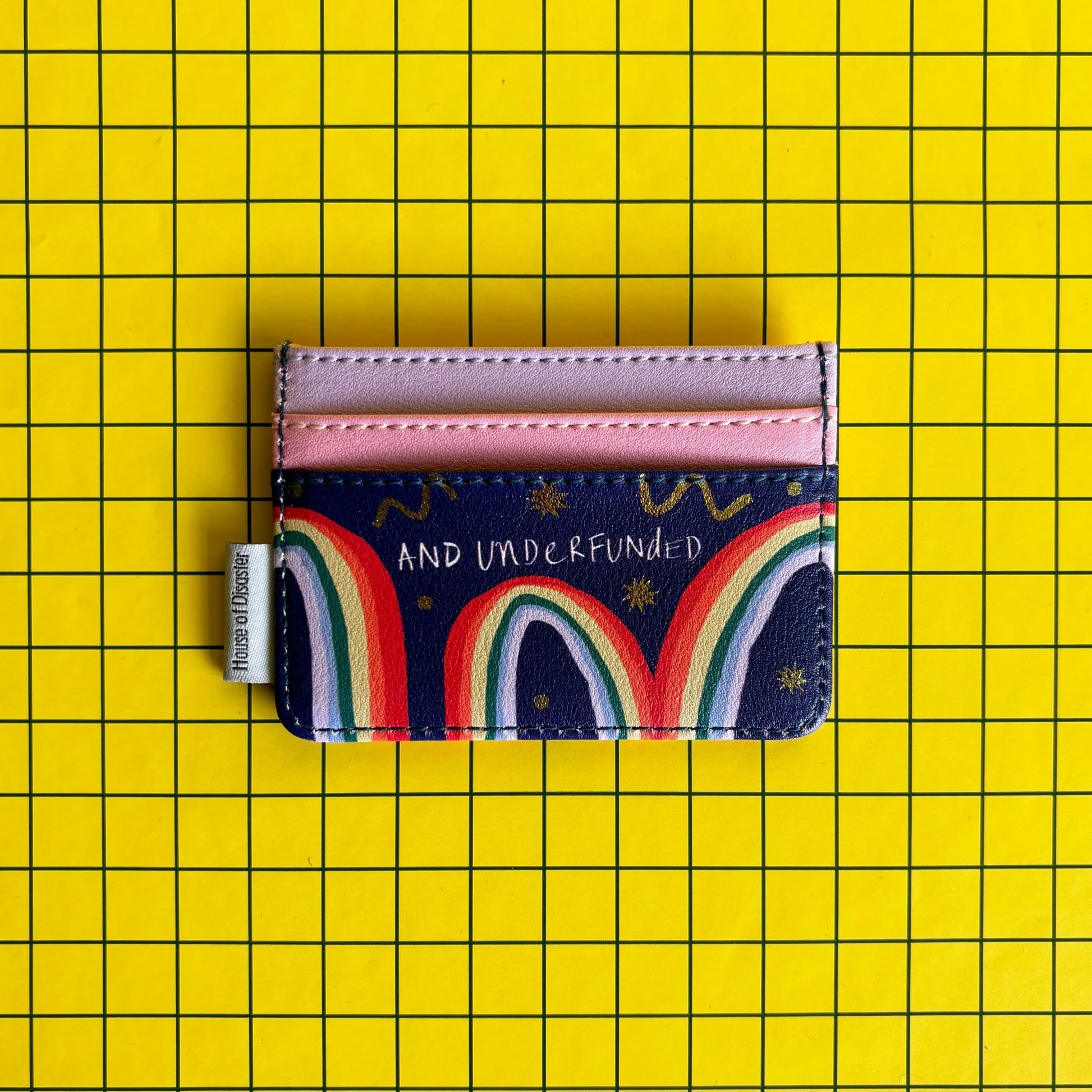 A multicoloured, pocket-sized cardholder with pink slots and AND UNDERFUNDED text, set on a yellow, grid-patterned background—a fun present for mates.