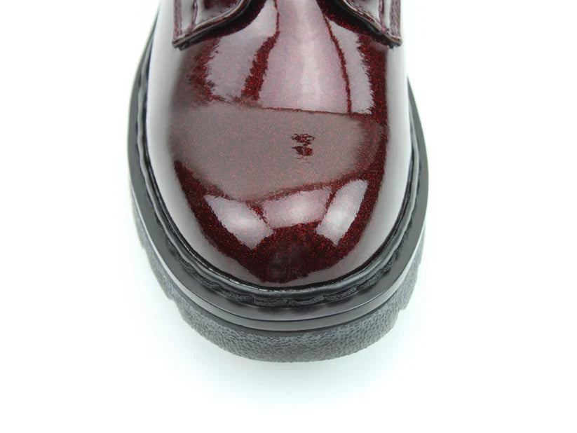 Close-up view of the toe and sole of a shiny, burgundy-coloured shoe with black trim and memory foam insoles, photographed against a white background.