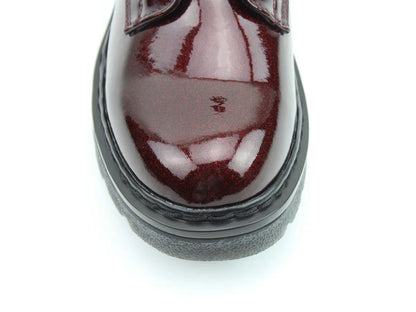 Close-up view of the toe and sole of a shiny, burgundy-coloured shoe with black trim and memory foam insoles, photographed against a white background.