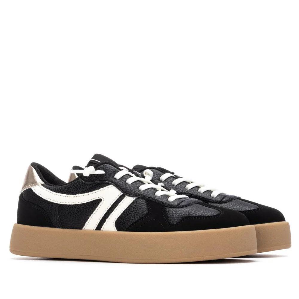 A pair of black low-top, PETA-certified vegan trainers with white side stripes, white laces, and tan non-slip rubber soles, shown side by side on a white background.