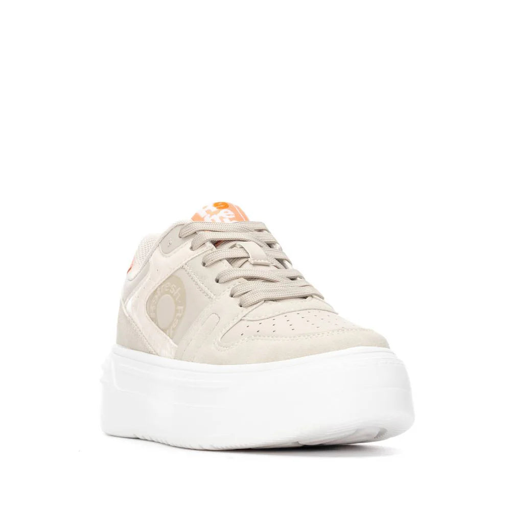 Beige vegan trainers with a chunky white sole, removable insole, beige laces, and orange logo accents on the tongue and side, seen from the front.