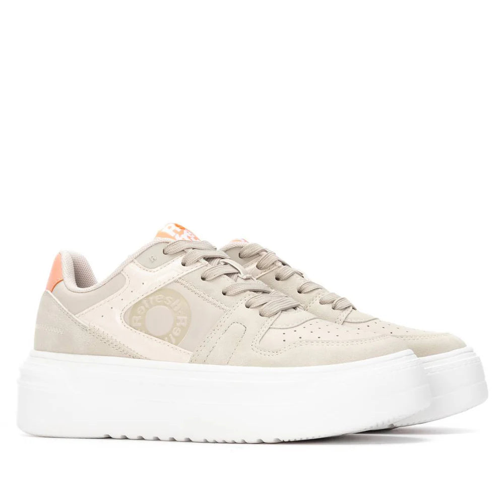 A pair of beige suede trainers with chunky white soles, light orange details on the heel and tongue, and a removable insole for extra comfort.